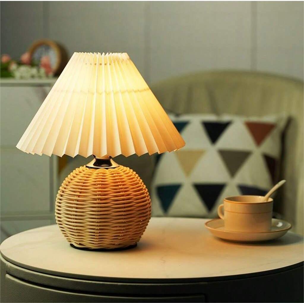 Rattan woven table lamp with pleated fabric shade on side table