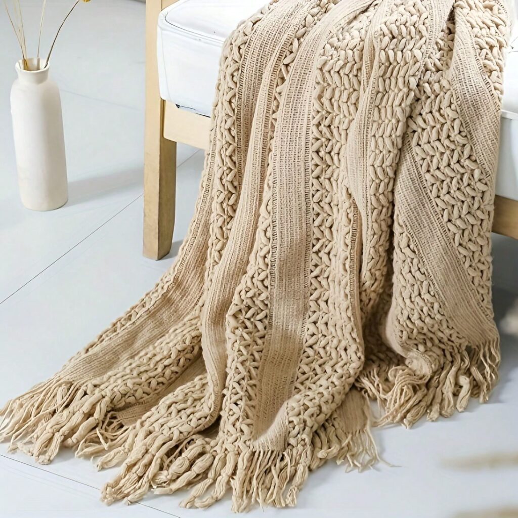 Chunky knit fringed throw blanket in beige draped over chair